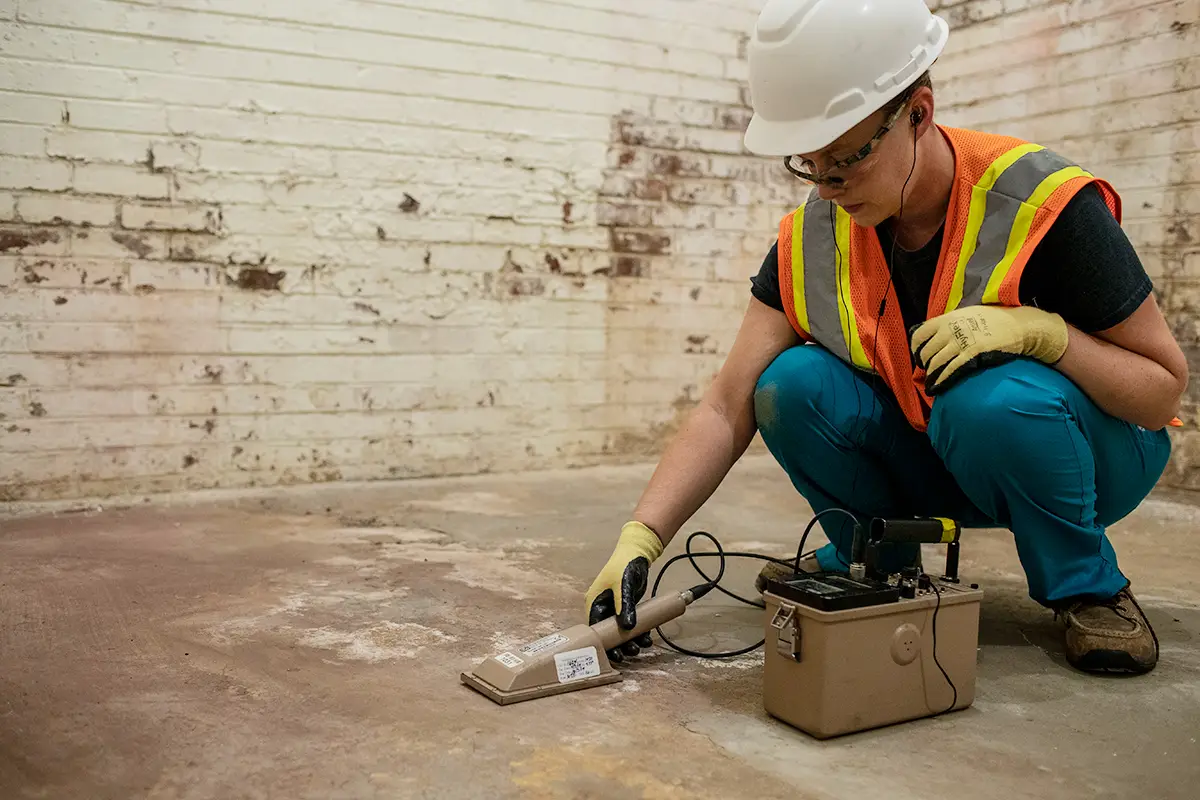 A female health physicist conducts an indoor radiation survey