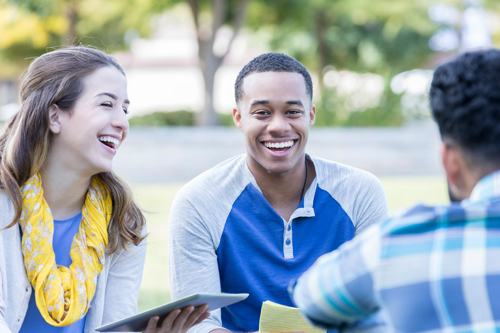 Young male college student sits outside in study group