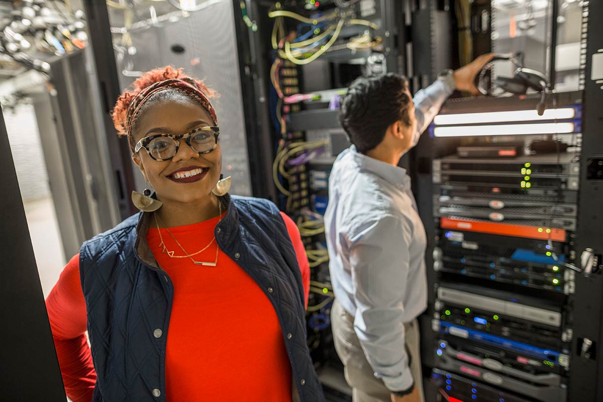 A woman and a man inspect IT equipment in a server room