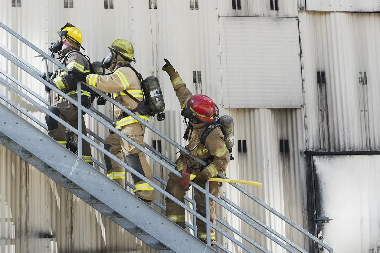 Firefighters climbing stairs outside industrial building