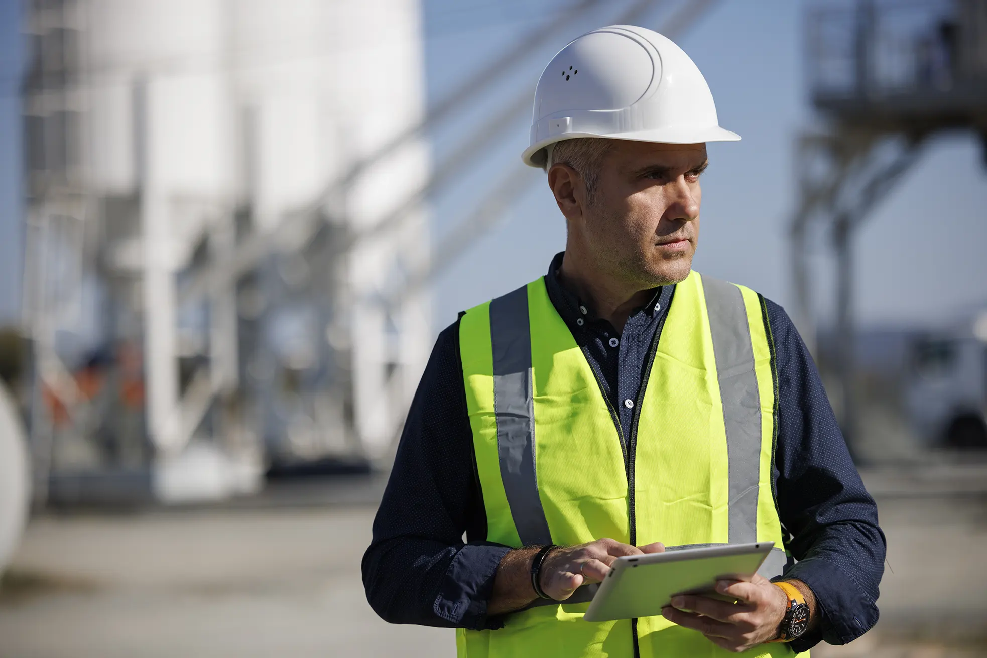 Man with hardhat using digital tablet while working on his work site