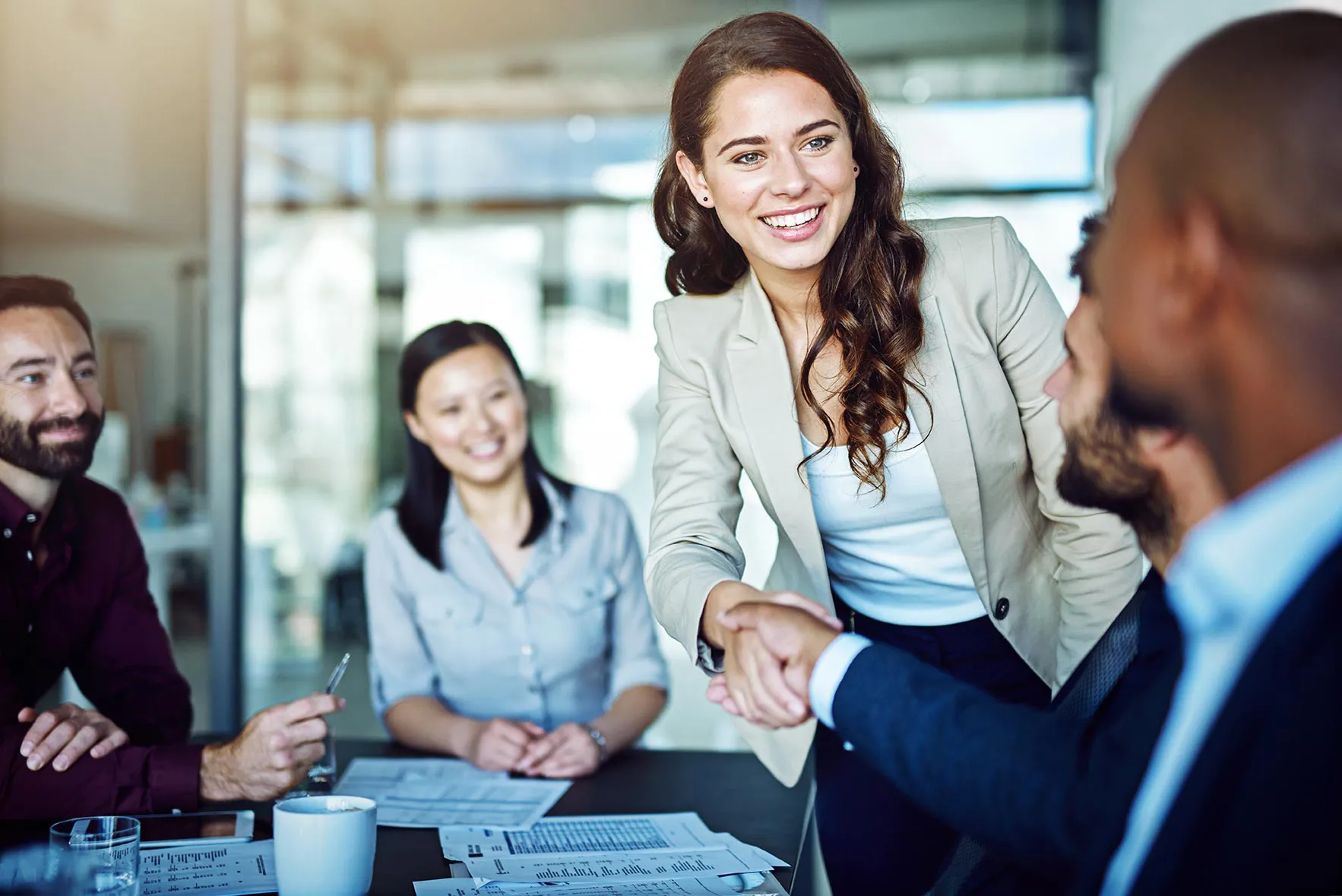 Two people shaking hands in larger group meeting
